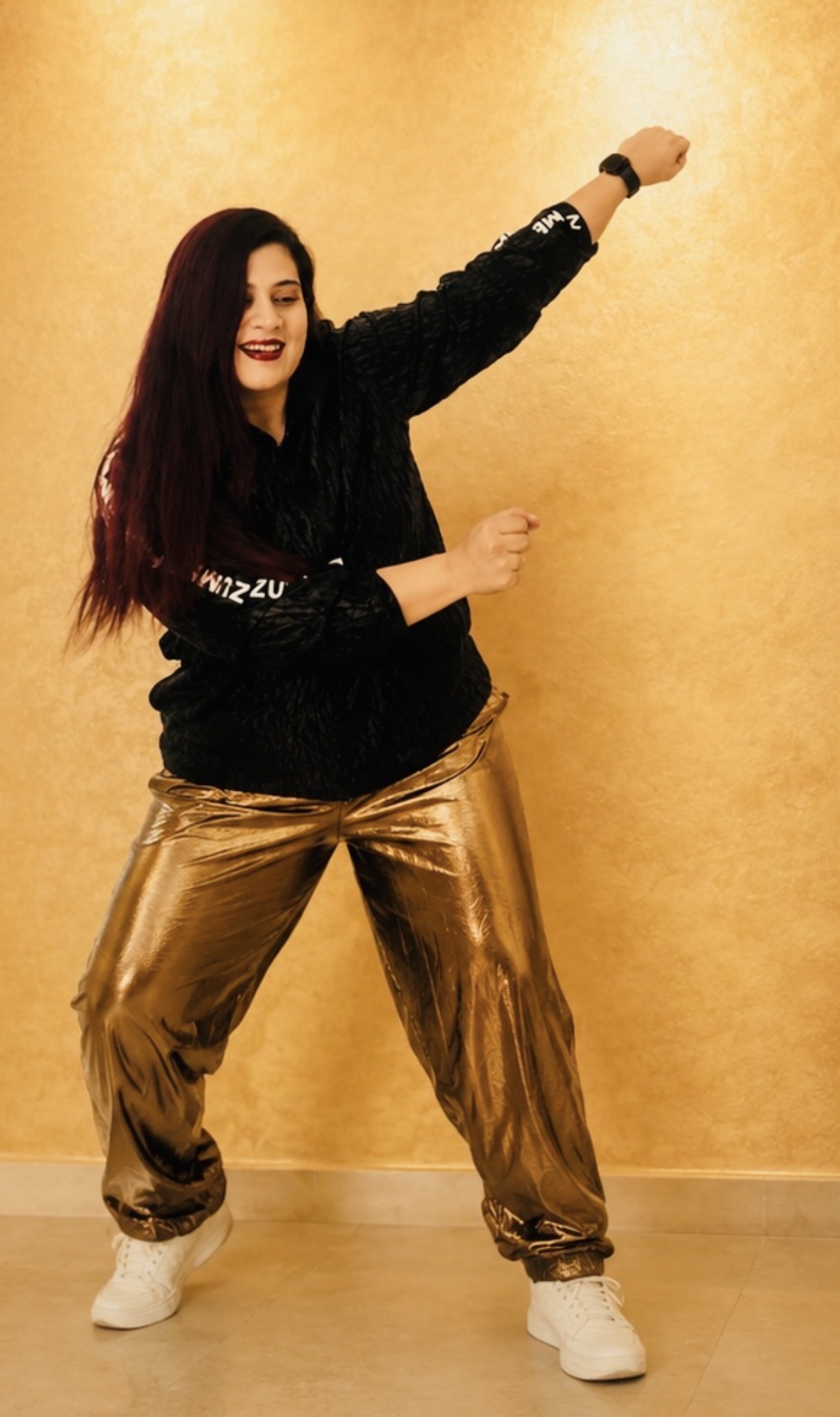 Swati dancing in a black top and gold trousers