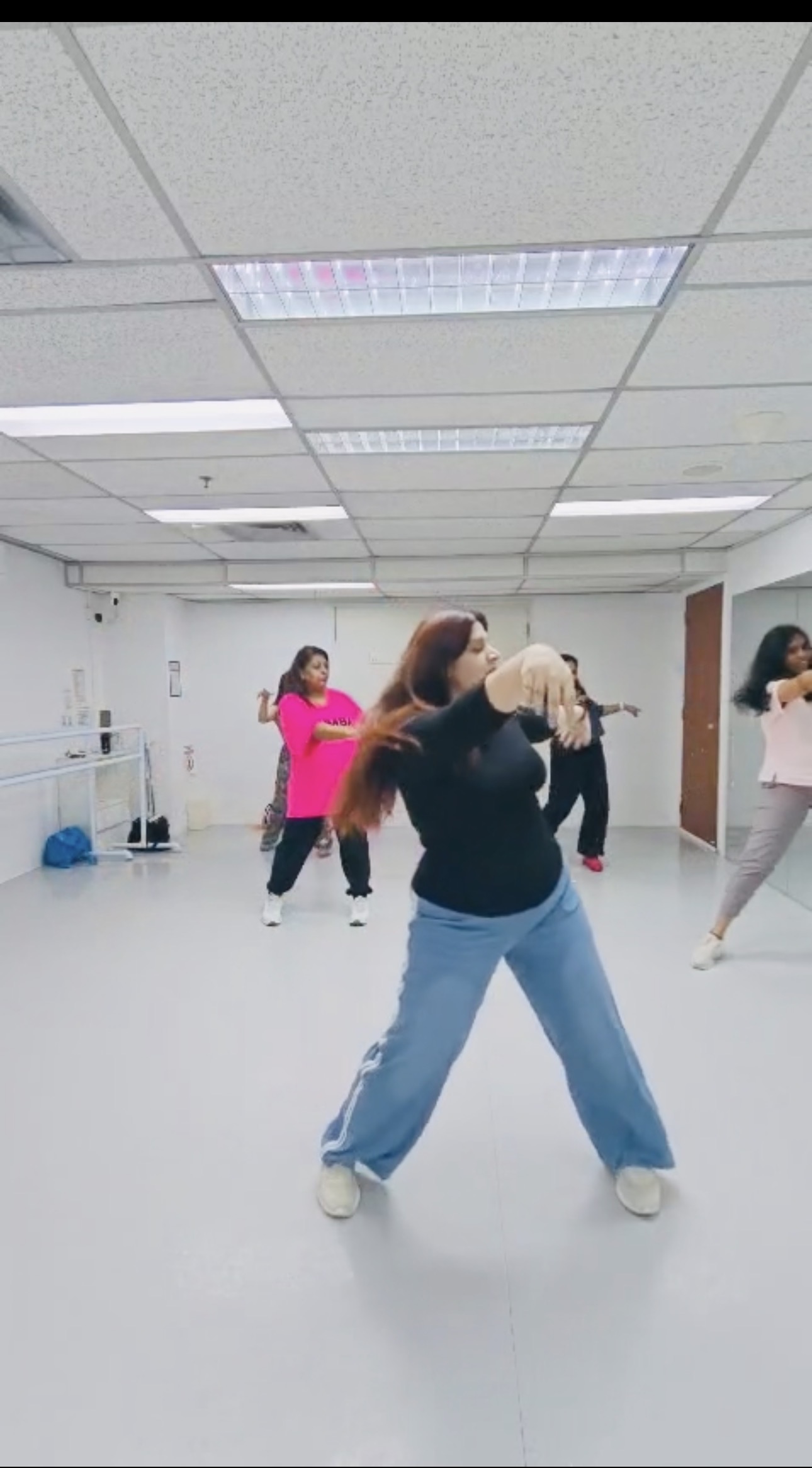 Swati leading a dance session in a black top and blue trousers